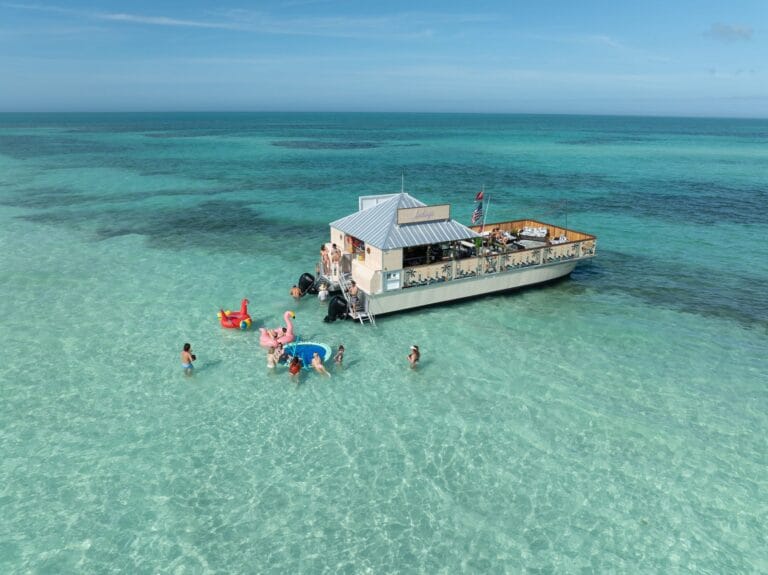 Docked houseboat with People Swimming and Playing in Clear Blue Ocean Water, Key West Boat Rentals, relaxing water activities and island cruising in Florida.