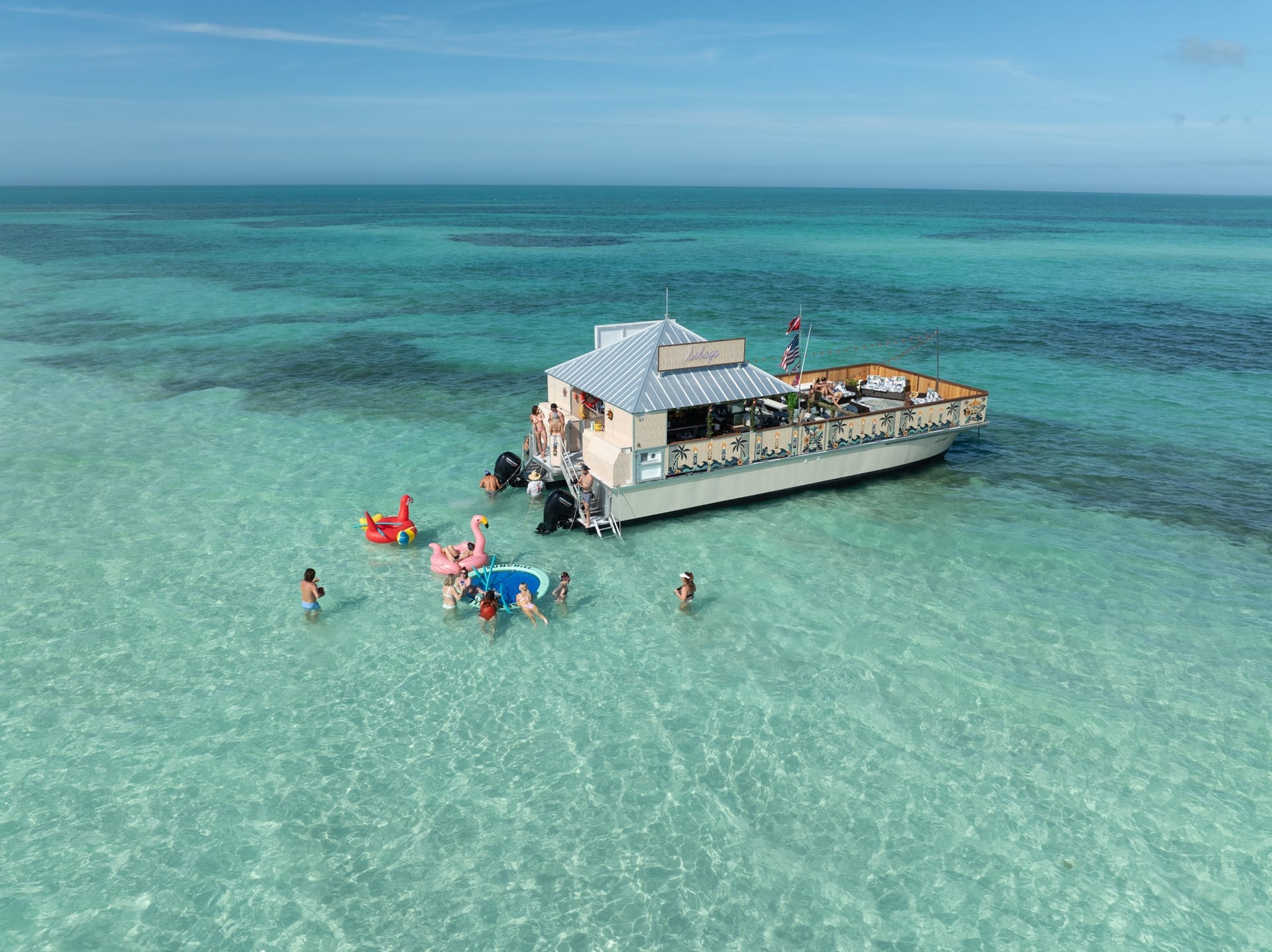 Docked houseboat with People Swimming and Playing in Clear Blue Ocean Water, Key West Boat Rentals, relaxing water activities and island cruising in Florida.